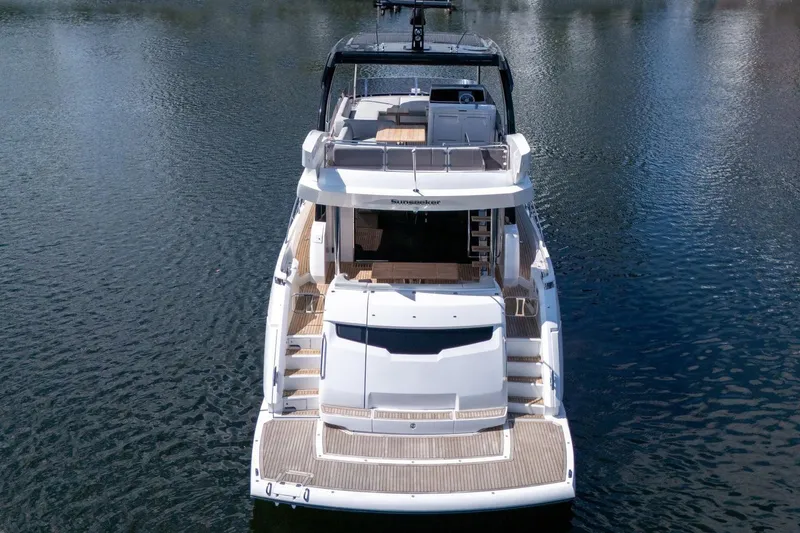 Slide: The Image of 2023 Sunseeker Manhattan 68 yacht on calm water, showcasing luxurious deck and seating area. - 11