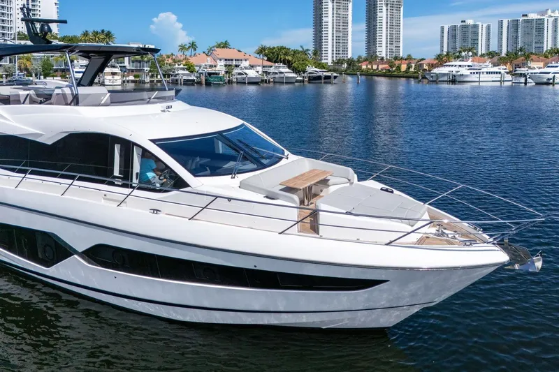 Slide: The Image of 2023 Sunseeker Manhattan 68 yacht deck with luxurious seating and scenic waterfront view. - 16