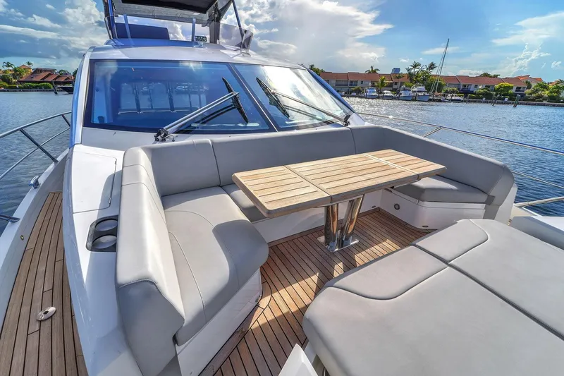 Slide: The Image of 2023 Sunseeker Manhattan 68 yacht with luxurious deck seating on a sunny waterfront. - 18