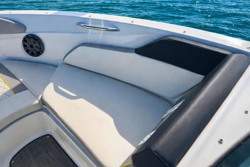 Slide: The Image of 2020 Glastron GTS 200 boat interior with cushioned seating and speaker, on blue water. - 13
