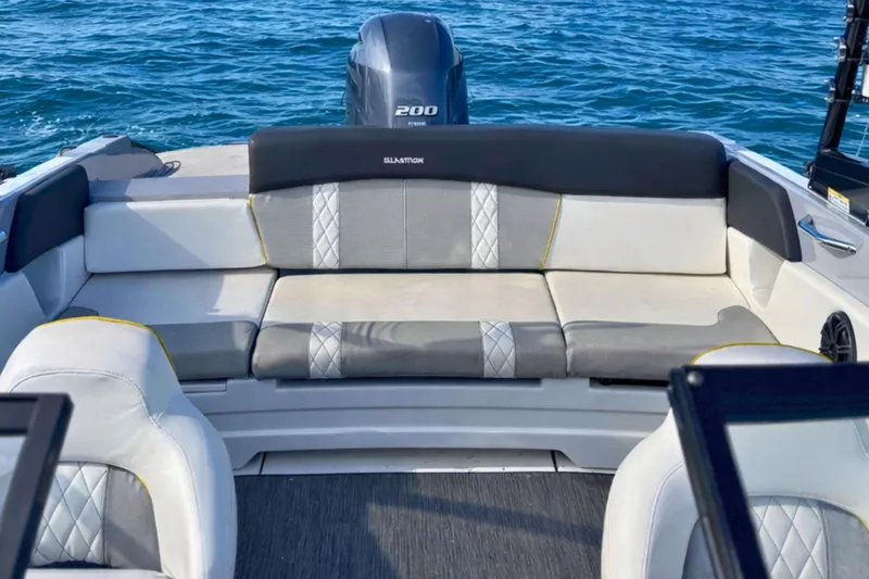 Slide: The Image of 2020 Glastron GTS 200 boat interior with cushioned seating and outboard motor on blue water. - 16