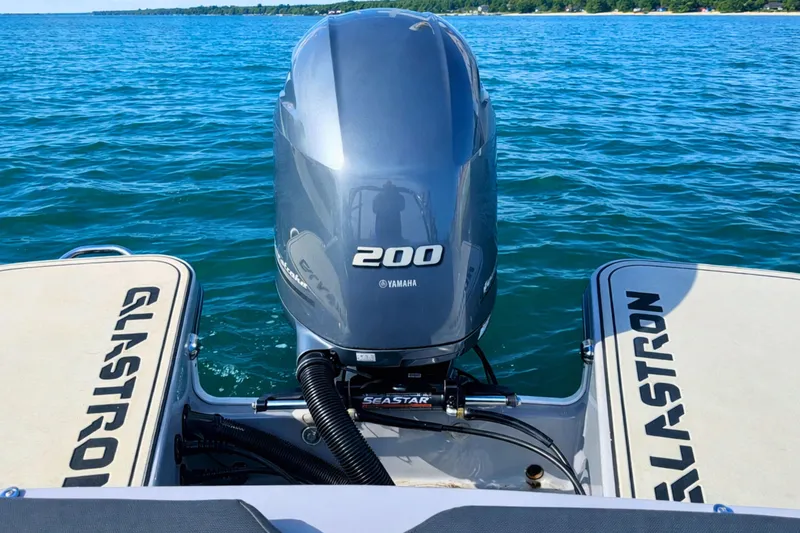 Slide: The Image of 2020 Glastron GTS 200 boat with Yamaha 200 engine on a serene lake. - 17