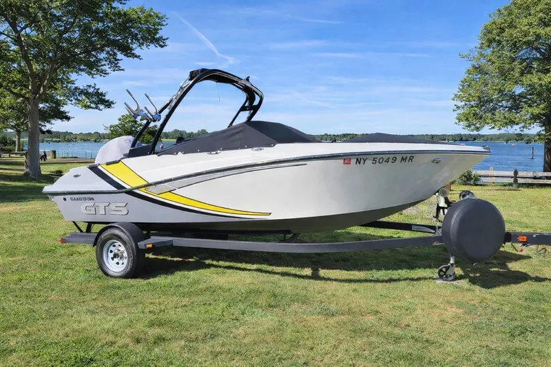Slide: The Image of 2020 Glastron GTS 200 boat on trailer, parked on grassy area by a lake. - 18