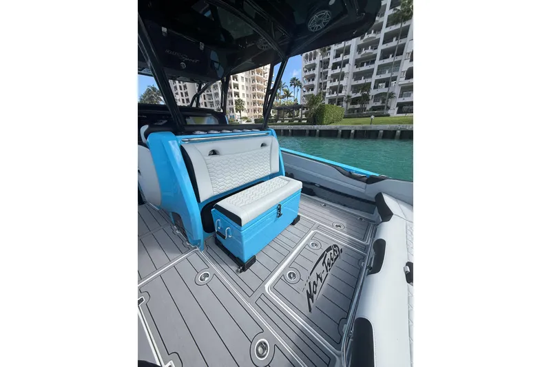 Slide: The Image of 2025 Nor-Tech 340 Sport Center Console interior with blue and white seating, dockside view. - 9