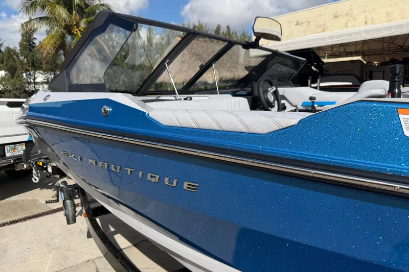 Slide: The Image of 2026 Nautique Ski Nautique boat in vibrant blue, parked outdoors with palm trees. - 3