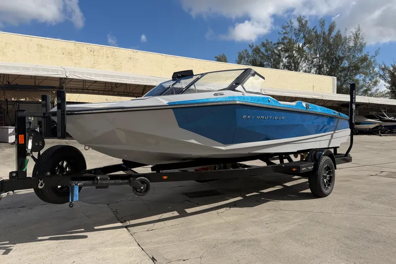 Slide: The Image of 2026 Nautique Ski Nautique boat on trailer, blue and white design, parked outdoors. - 4