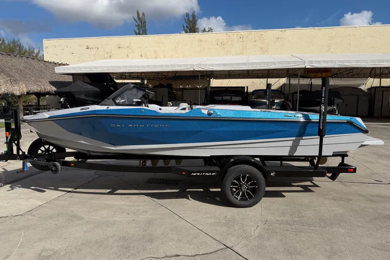 Slide: The Image of 2026 Nautique Ski Nautique boat on trailer, blue and white design, parked outdoors. - 7