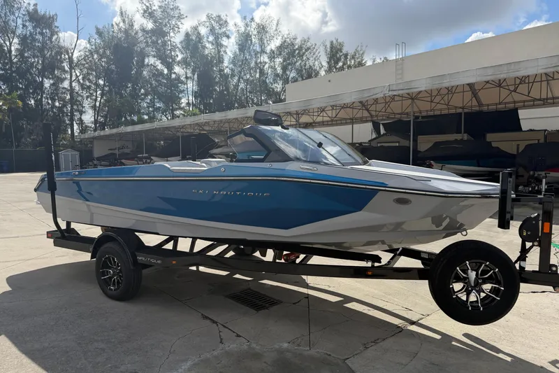 Slide: The Image of 2026 Nautique Ski Nautique boat on trailer, blue and white design, parked outdoors. - 8