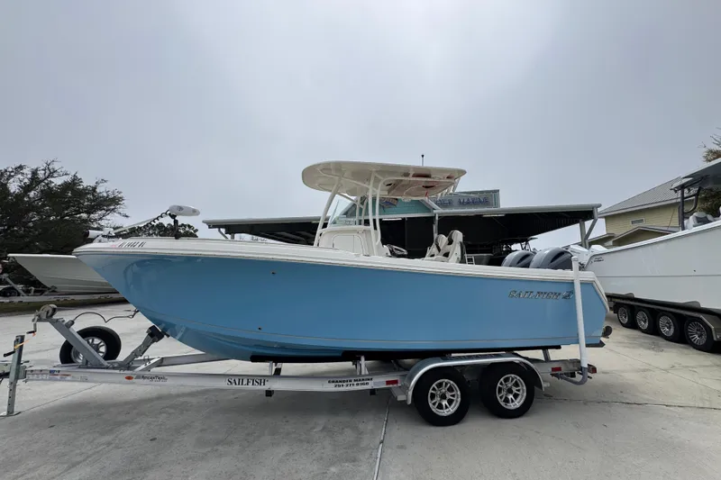 The Image of 2022 Sailfish 242 CC boat on trailer, light blue hull, parked outdoors. - 1