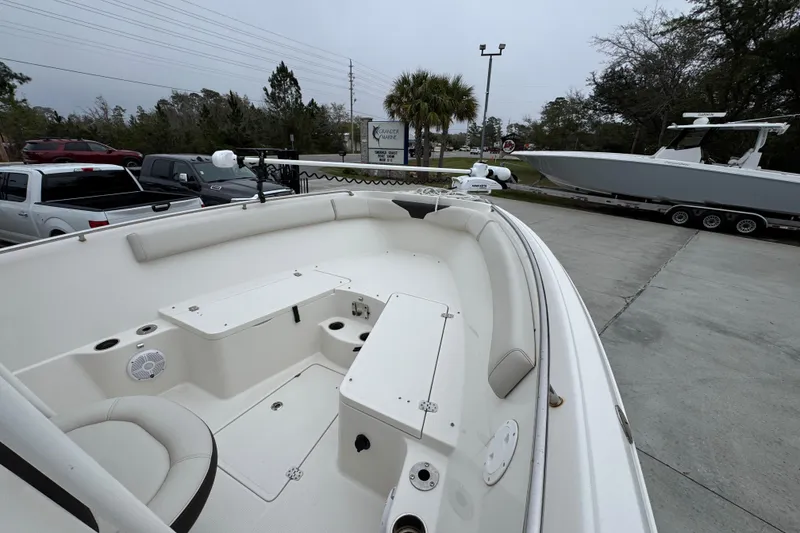 Slide: The Image of 2022 Sailfish 242 CC boat interior with seating and storage, parked outdoors. - 14