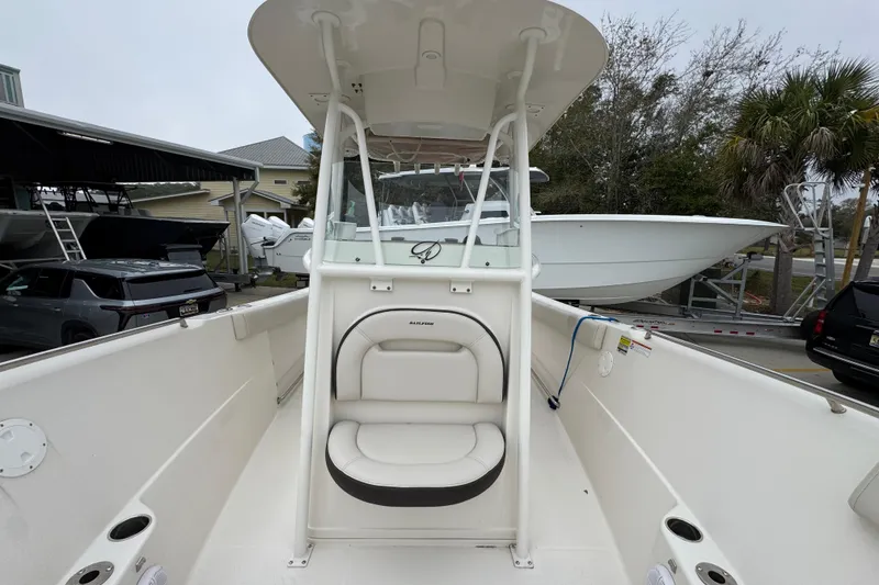 Slide: The Image of 2022 Sailfish 242 CC boat interior with seating and console, parked outdoors. - 20