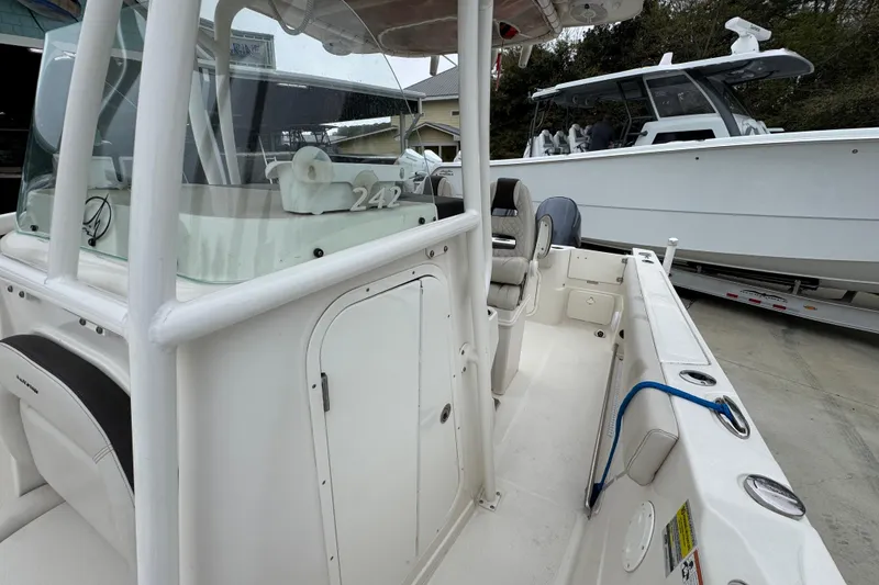 Slide: The Image of 2022 Sailfish 242 CC boat interior with seating and console, docked beside another vessel. - 21