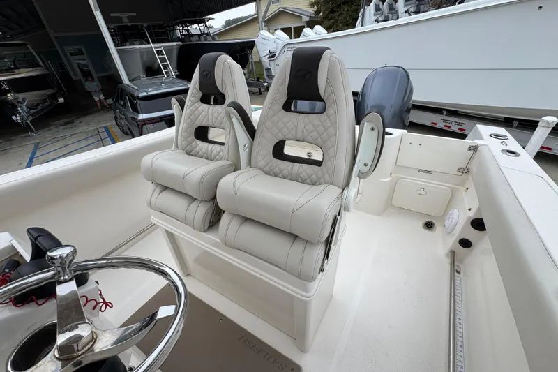 Slide: The Image of 2022 Sailfish 242 CC boat interior with dual cushioned seats and steering wheel. - 24