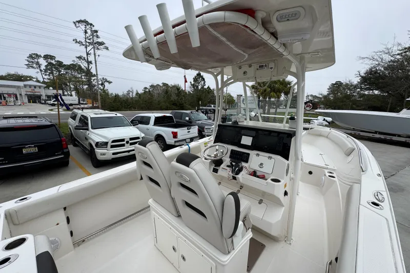Slide: The Image of 2022 Sailfish 242 CC boat interior with dual seats and control panel, parked near vehicles. - 35