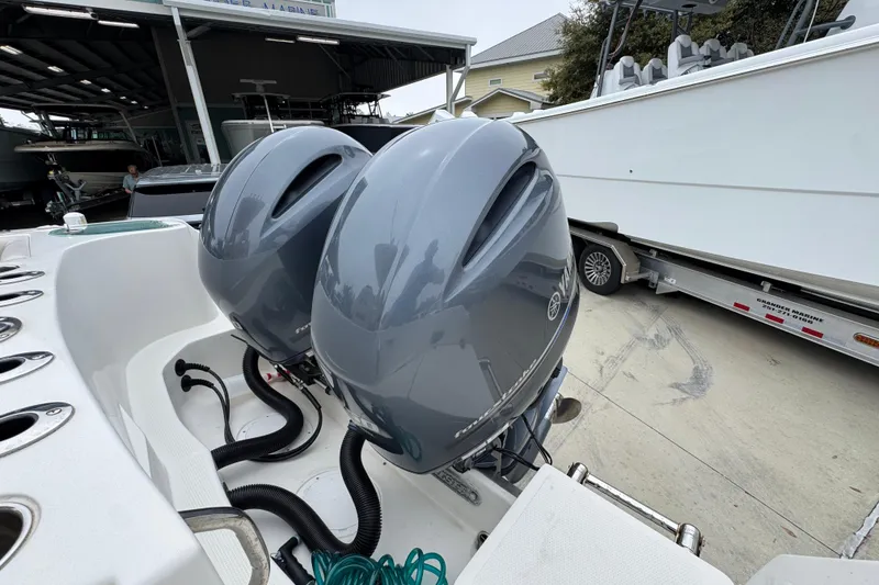 Slide: The Image of Twin outboard motors on a 2022 Sailfish 242 CC boat, parked at a marina. - 39