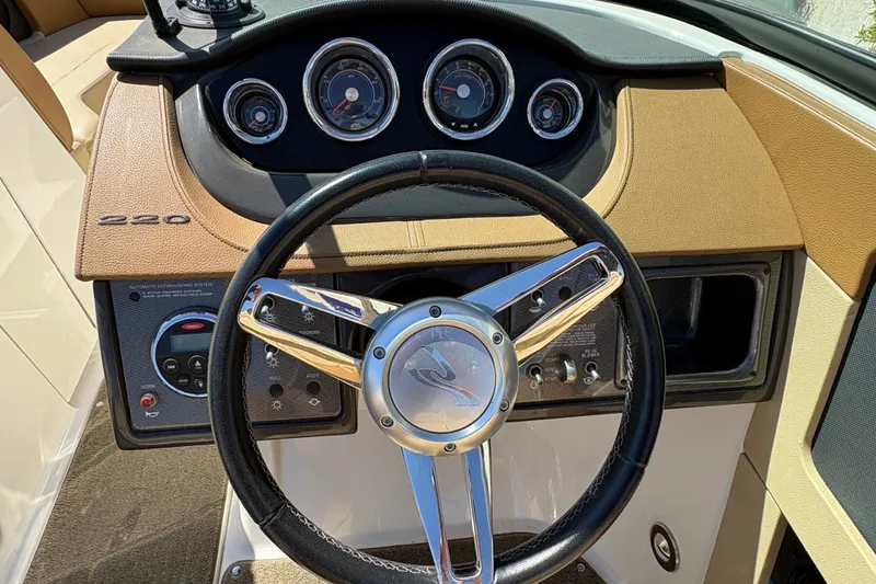 Slide: The Image of 2015 Sea Ray 220 Sundeck dashboard with steering wheel and instrument panel. - 15