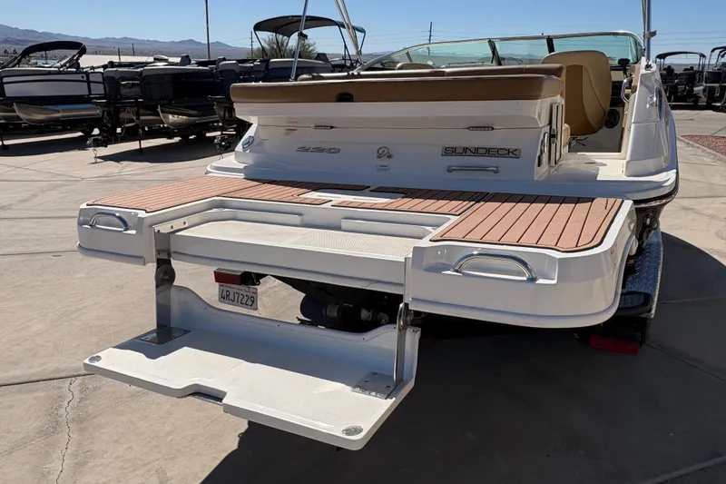 Slide: The Image of 2015 Sea Ray 220 Sundeck boat with extended swim platform in a marina setting. - 7