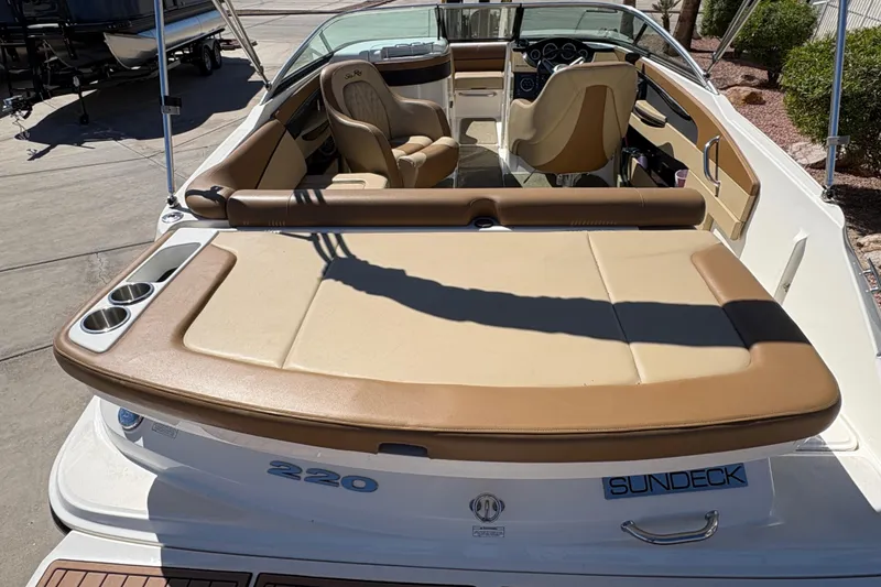 Slide: The Image of 2015 Sea Ray 220 Sundeck boat with tan seating and cup holders, docked outdoors. - 8