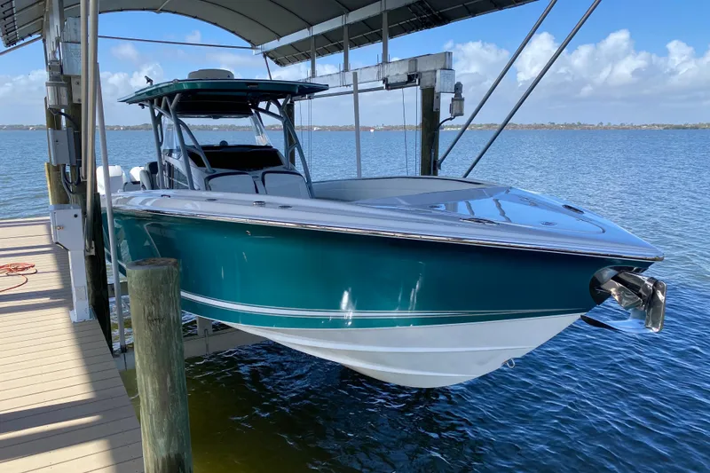 Slide: The Image of 2018 Nor-Tech 340 Sport Center Console boat docked on a lift over water. - 2