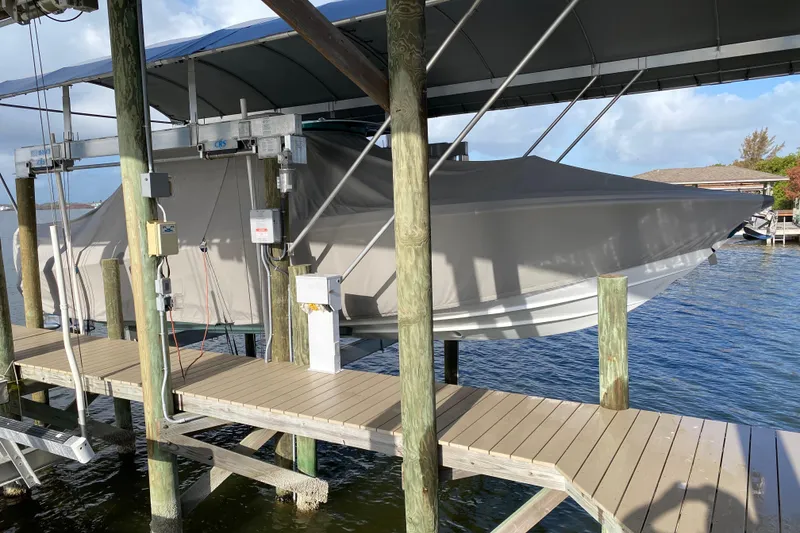 Slide: The Image of 2018 Nor-Tech 340 Sport Center Console boat covered and docked on a lift. - 26