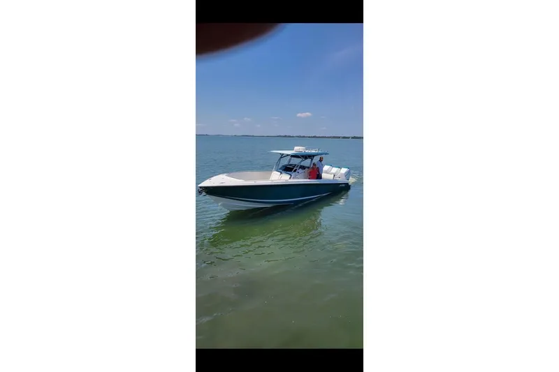 Slide: The Image of 2018 Nor-Tech 340 Sport Center Console boat on calm water under clear sky. - 30