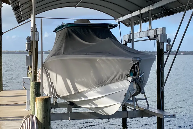 Slide: The Image of 2018 Nor-Tech 340 Sport Center Console boat covered on a lift by the water. - 4