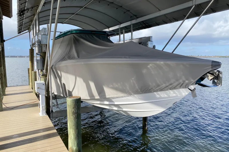 Slide: The Image of 2018 Nor-Tech 340 Sport Center Console boat covered and docked on a lift. - 5