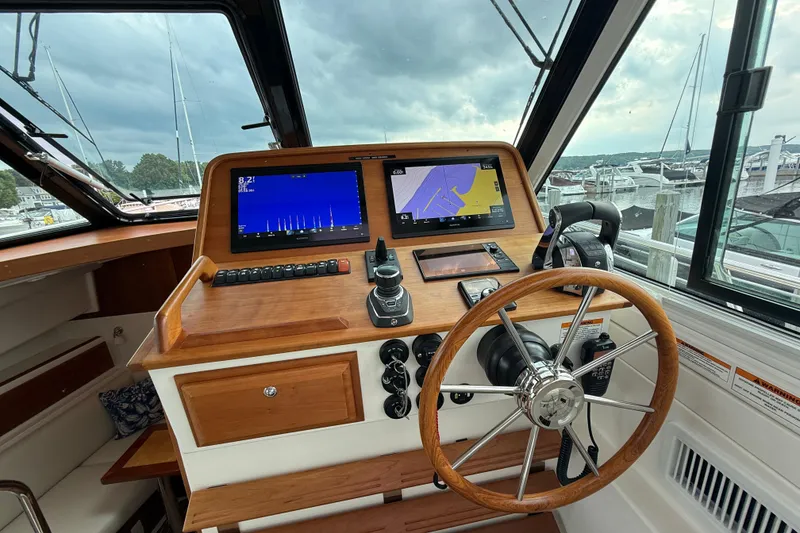 Slide: The Image of Helm of 2022 Back Cove 39O boat with modern navigation displays and wooden steering wheel. - 44