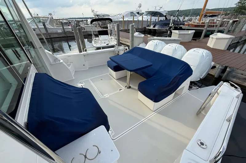 Slide: The Image of 2022 Back Cove 39O boat with blue-covered seating and triple outboard engines at a marina. - 18
