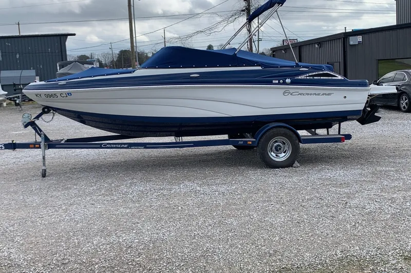 The Image of 2018 Crownline 205 SS boat on trailer, parked outdoors, blue and white design. - 0