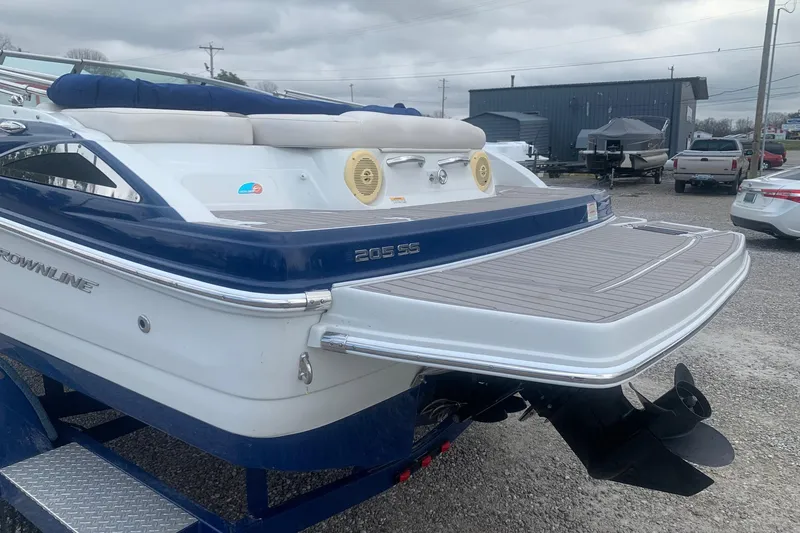 Slide: The Image of 2018 Crownline 205 SS boat with swim platform and outboard motor, parked outdoors. - 6