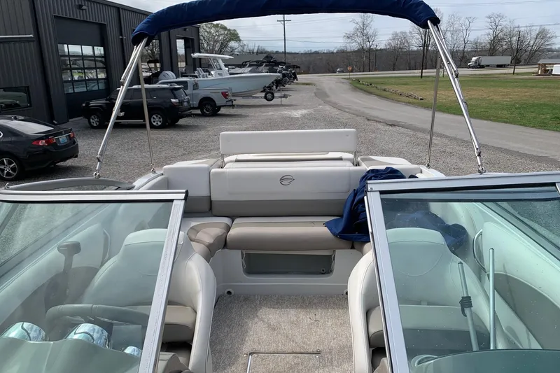 Slide: The Image of 2018 Crownline 205 SS boat interior with seating and canopy, parked near a dealership. - 8