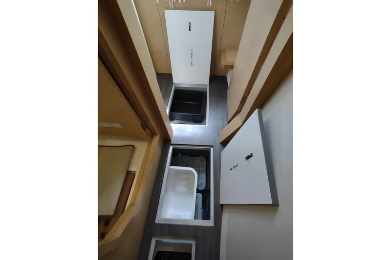Slide: The Image of Interior storage compartments of a 2020 Outremer 51 catamaran, featuring open hatches and organized spaces. - 127