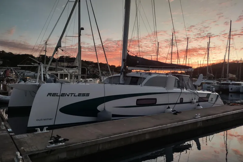 Slide: The Image of 2020 Outremer 51 catamaran docked at sunset, showcasing sleek design and vibrant sky. - 13