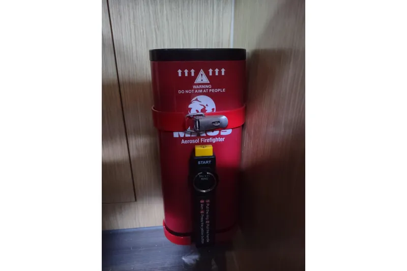 Slide: The Image of Red aerosol firefighter canister on Outremer 51 yacht, 2020 model, secured to wooden wall. - 156