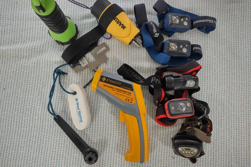 Slide: The Image of Assorted tools and headlamps on a patterned surface, featuring an Etekcity infrared thermometer. - 163