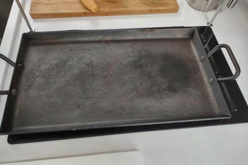 Slide: The Image of Cast iron griddle on induction cooktop, with wooden cutting board in background. - 167