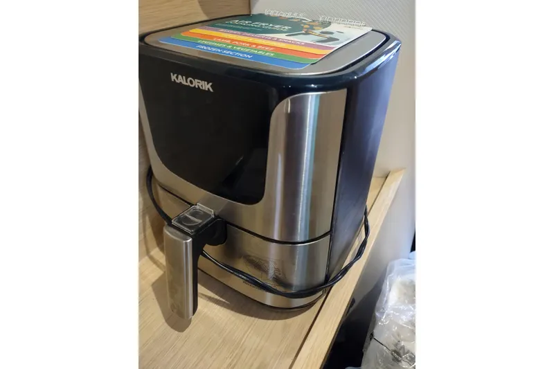 Slide: The Image of Kalorik air fryer on wooden shelf, stainless steel design, modern kitchen appliance. - 184