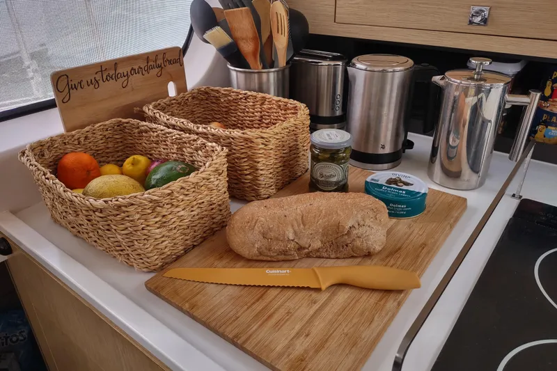 Slide: The Image of Kitchen counter with bread, fruit baskets, and kitchen utensils on an Outremer 51 yacht. - 60
