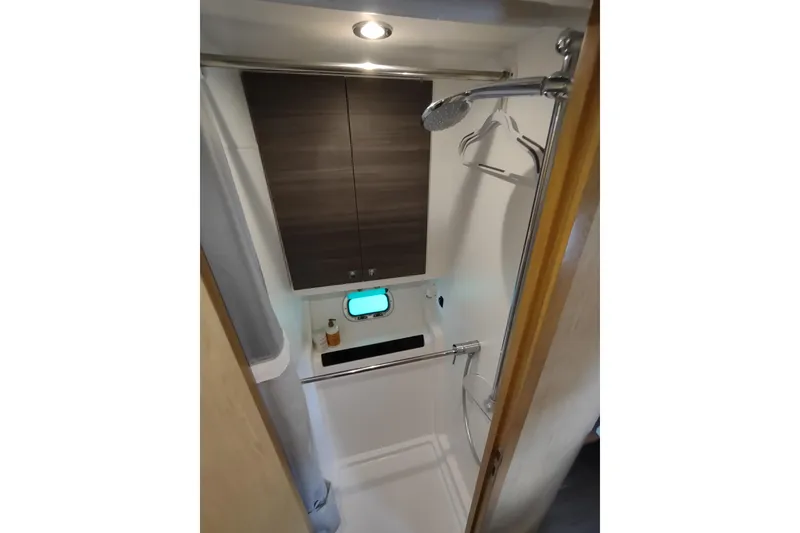 Slide: The Image of 2020 Outremer 51 yacht bathroom with shower, wooden cabinets, and porthole window. - 70