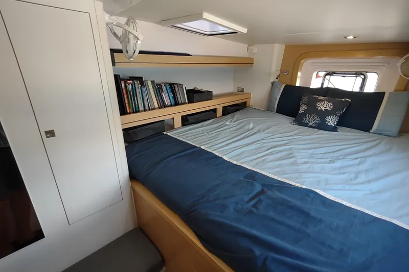 Slide: The Image of Cozy bedroom in 2020 Outremer 51 yacht with bookshelf and blue bedding. - 77