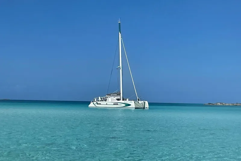 Slide: The Image of 2020 Outremer 51 catamaran anchored in clear turquoise waters under a bright blue sky. - 8