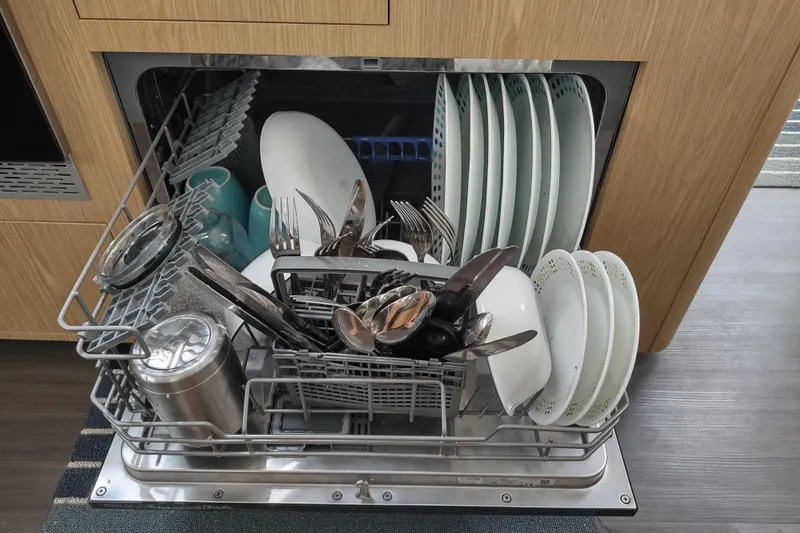 Slide: The Image of Dishwasher loaded with plates, cutlery, and cups in a modern kitchen setting. - 95