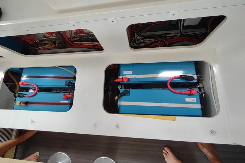 Slide: The Image of Battery compartment of a 2020 Outremer 51 catamaran, showcasing blue batteries and wiring. - 96