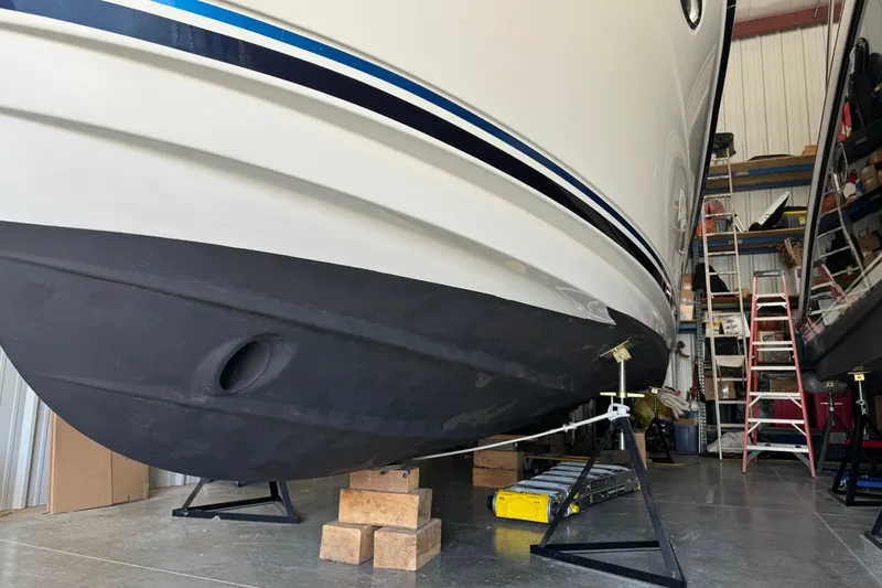 Slide: The Image of 2017 Cutwater C-30 Sedan boat in storage, supported by stands, with visible hull and ladder. - 3
