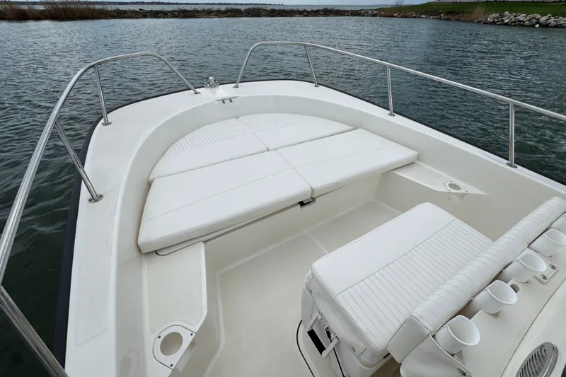 Slide: The Image of 2016 Boston Whaler 210 Montauk boat interior with white seating and railing on calm water. - 11