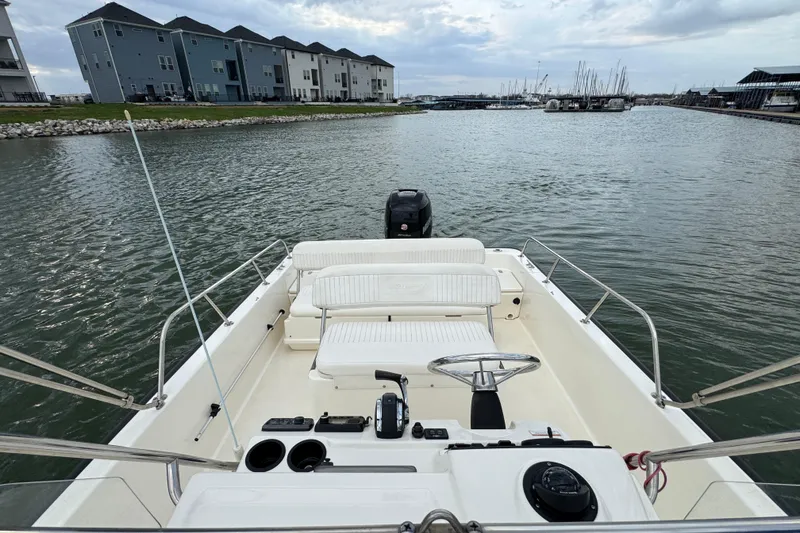 Slide: The Image of 2016 Boston Whaler 210 Montauk boat on calm water near modern waterfront buildings. - 12
