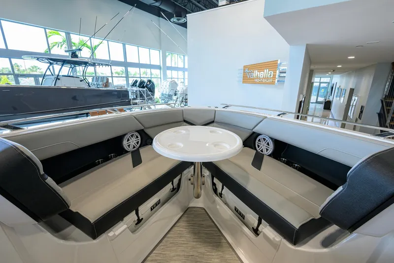 Slide: The Image of Interior of 2026 Monterey Elite 30 OB boat with seating and table in showroom. - 16
