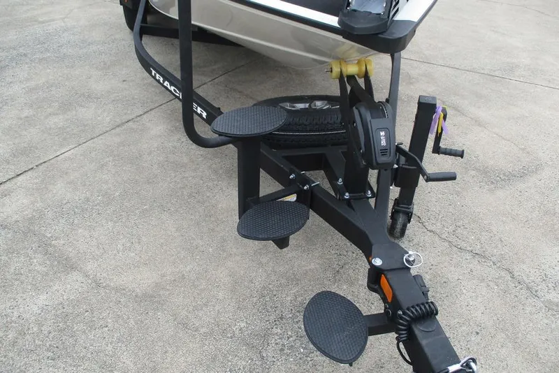 Slide: The Image of 2026 Tracker Savage 215 boat trailer with steps and winch on concrete surface. - 14