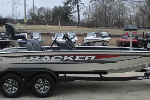 Slide: The Image of 2026 Tracker Savage 215 boat on trailer, parked outdoors with other boats in the background. - 3